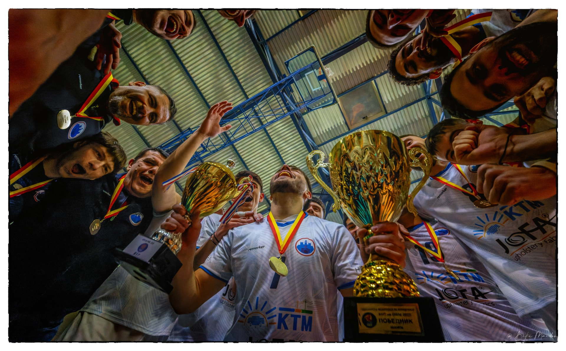 Team huddle celebrating with medals and trophy